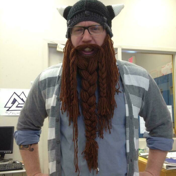 Man dressed as a funny teacher wearing a Viking hat and braided yarn beard in a classroom setting.