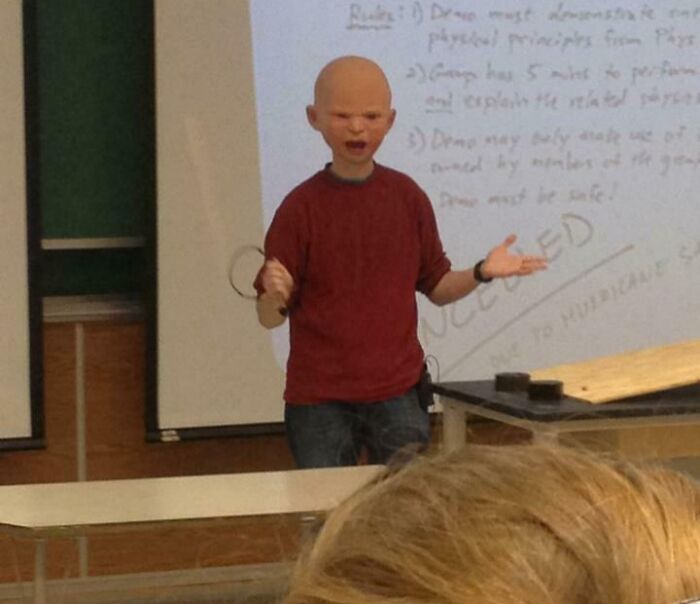 Teacher wearing a funny mask in classroom, engaging students with humor during a science lesson.