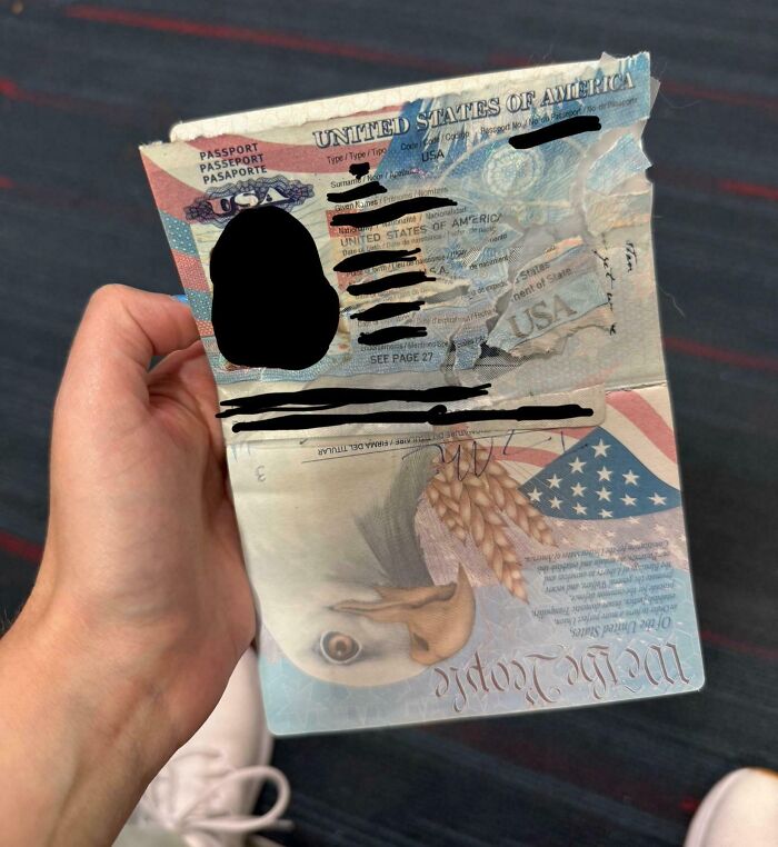 Damaged US passport held by a person showing torn pages, illustrating worst luck on vacation mishaps.