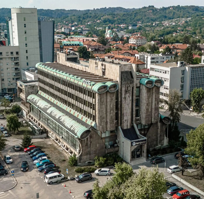 Aerial view of a large brutalist building in an urban area reflecting themes of urban hell and societal decay.