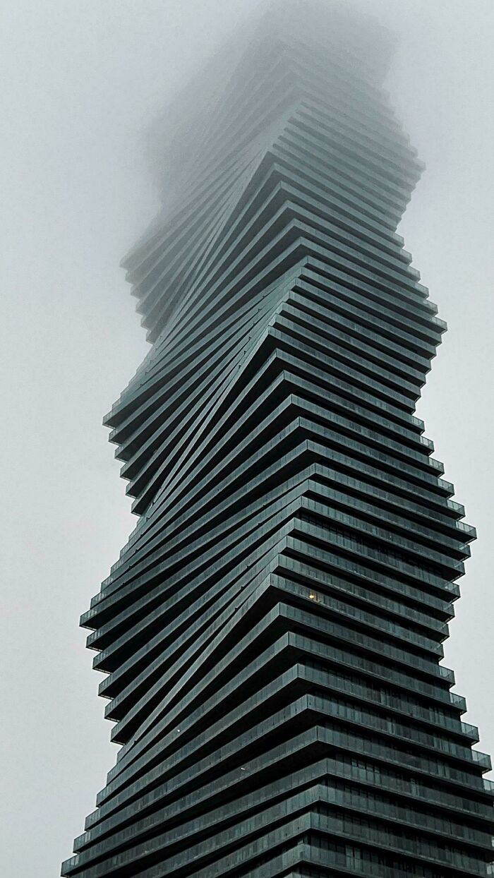 Twisted dark modern building shrouded in fog, resembling an evil building from horror movies with an eerie atmosphere.