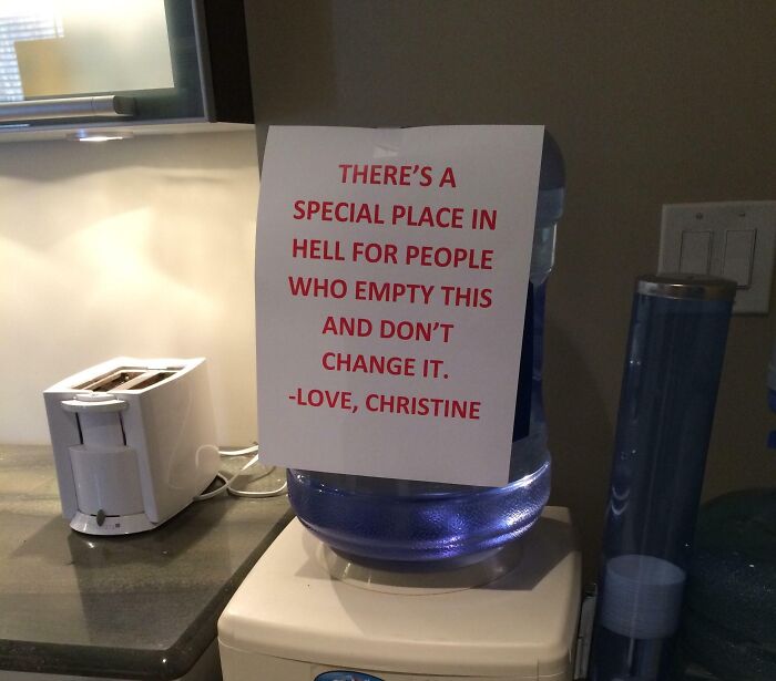 Passive-aggressive coworker note on water cooler expressing frustration about not changing empty water bottles.