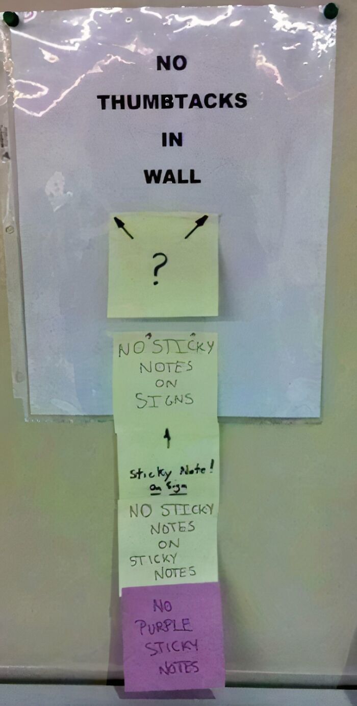 Passive-aggressive coworker notes stacked on a wall sign, showing frustration with thumbtacks and sticky notes usage.