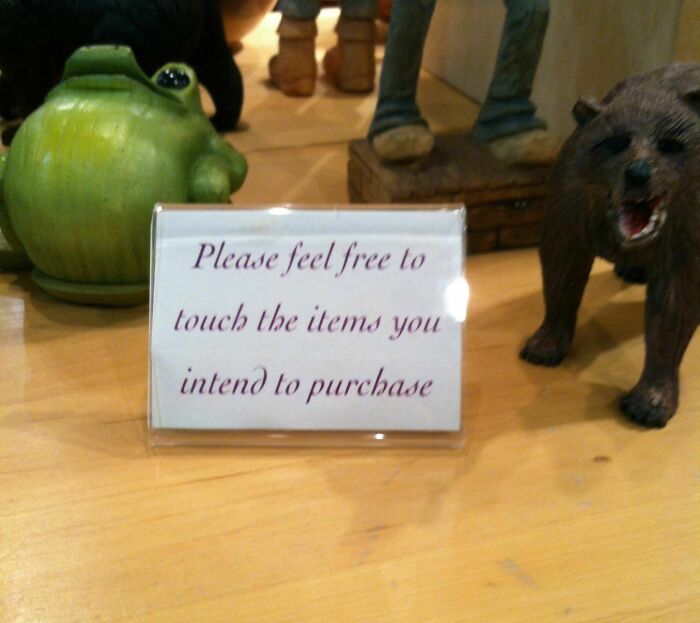 Passive-aggressive note on a store counter sarcastically inviting customers to touch items only if they intend to purchase.