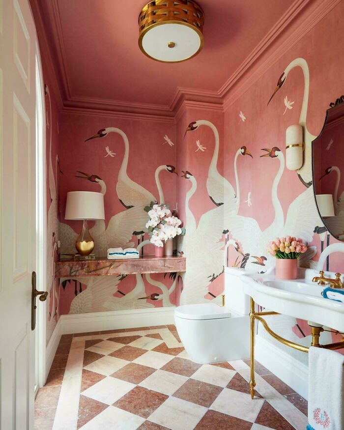 Bathroom with pink crane wallpaper, decorative flowers, gold accents, and elegant home decor showcasing proud home decoration.