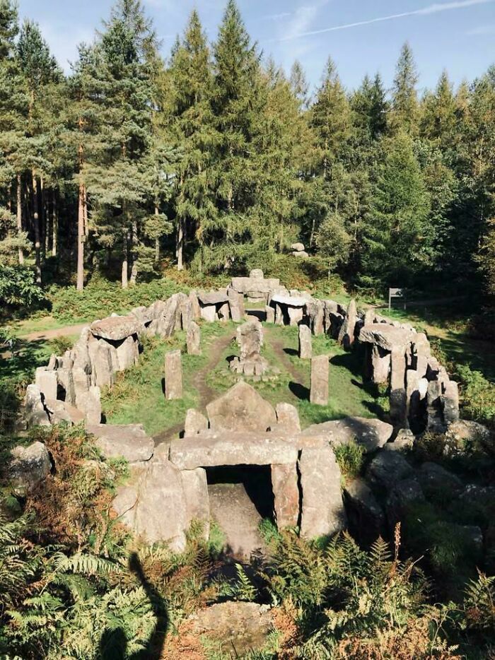 Ancient stone circle ruins surrounded by dense green forest under clear sky at devil sunrise location.