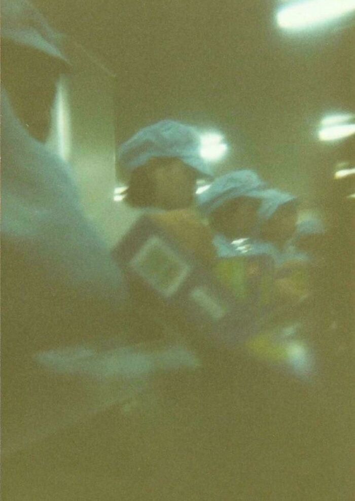 Blurry image of workers in uniforms and caps inside a dimly lit room, capturing a mysterious devil sunrise vibe.