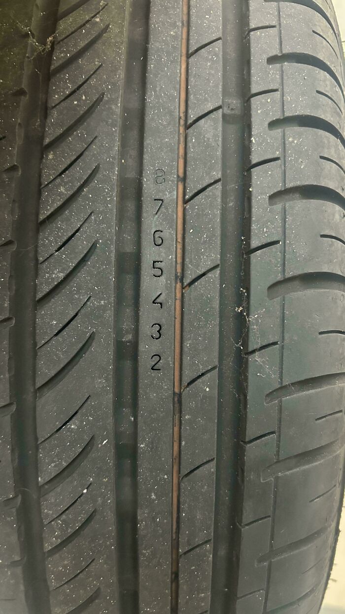 Close-up of a car tire tread showing wear indicator numbers for safe driving and maintenance guidance.