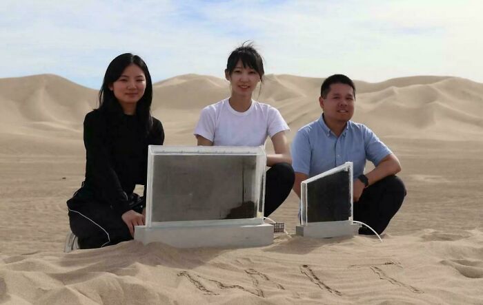 Three people sitting in a desert setting with reflective glass panels, illustrating a devil sunrise effect concept.