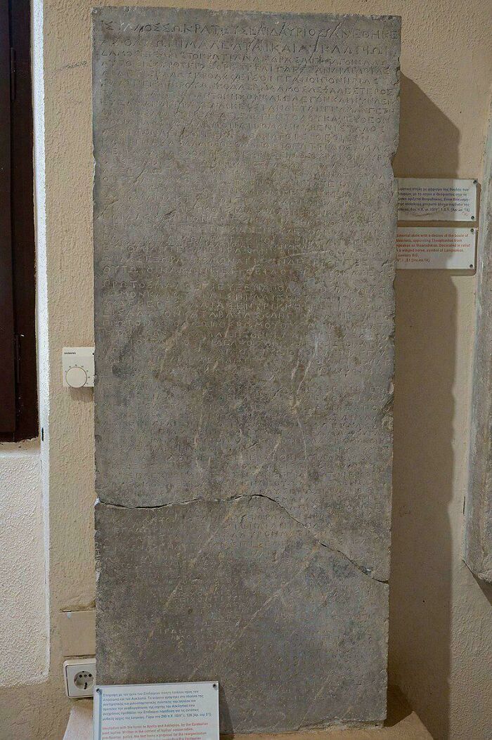 Ancient stone inscription still remains undiscovered to this day, featuring faint Greek text on a museum wall.