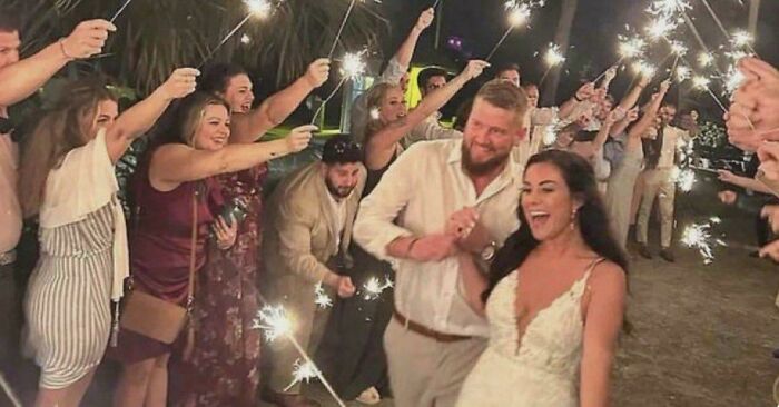 Couple celebrating with sparklers at night surrounded by guests in a joyful moment still remains undiscovered to this day.