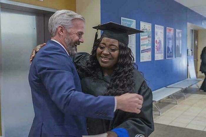 Man in blue suit congratulating smiling woman in graduation cap and gown, celebrating achievements still remains undiscovered.