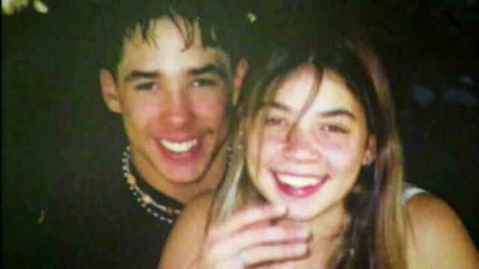 Two young people smiling closely together in a casual setting, capturing a moment that still remains undiscovered to this day.