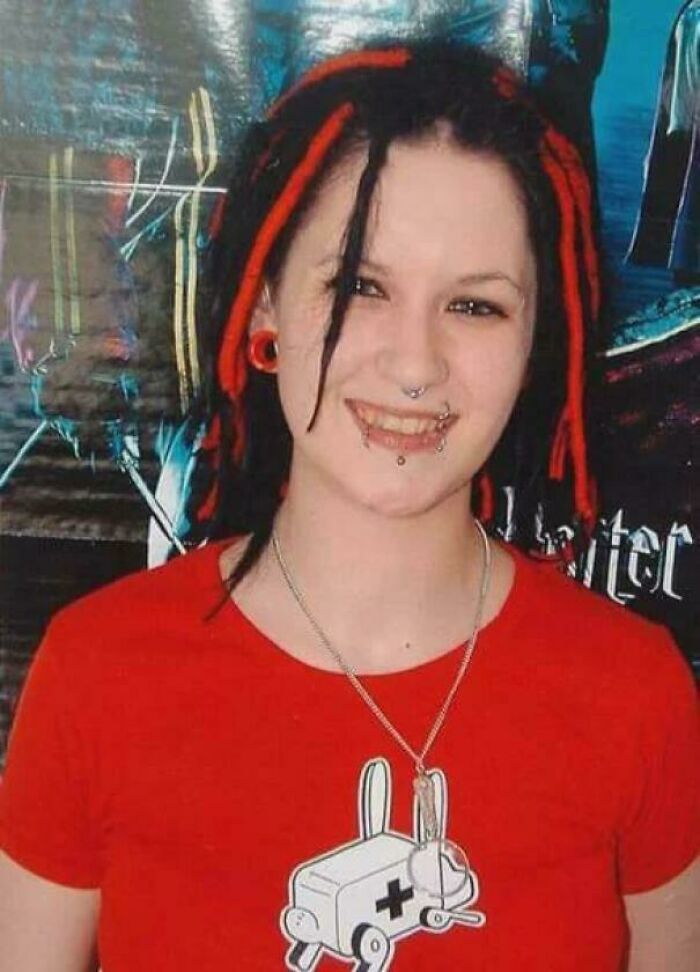 Young woman with red and black dreadlocks, wearing piercings and a red shirt, smiling with vibrant background still remains undiscovered.