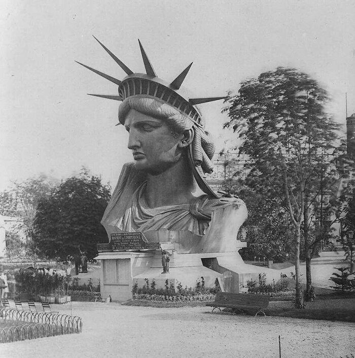 An extremely large head of the Statue of Liberty displayed in a park, making the things scary and eerie.