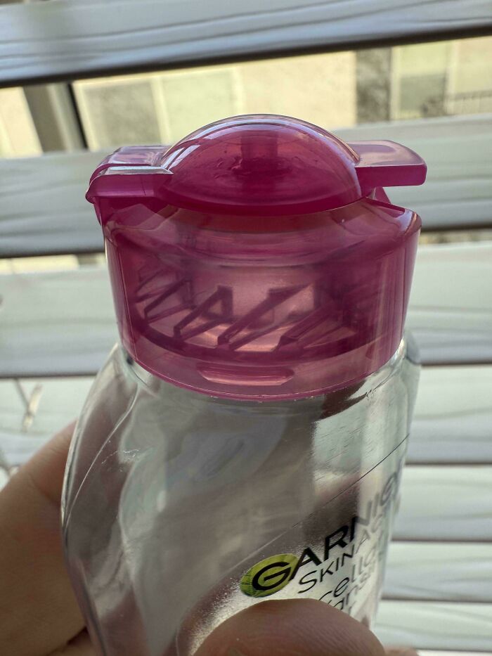 Close-up of a plastic Garnier bottle with a purple cap, highlighting the impact of consumerism and waste.