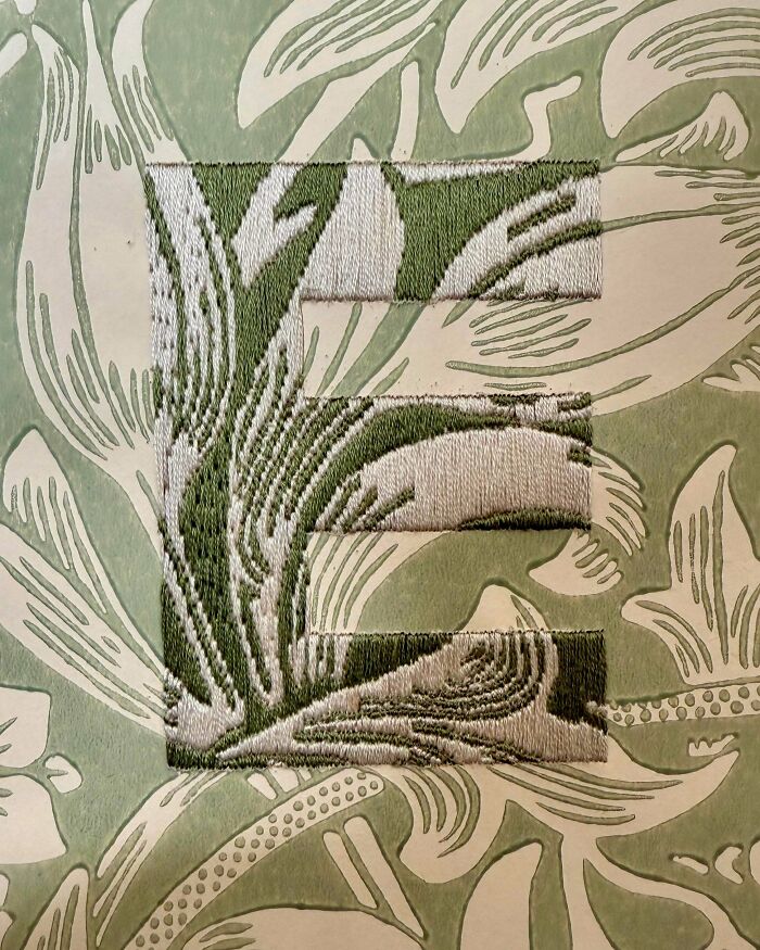 A stunning embroidery creation of the letter E in green and white, a fine example of embroidery creations.