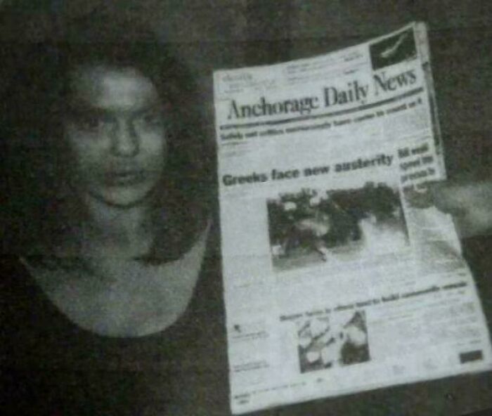 Woman holding a newspaper in a dimly lit room, highlighting facts that still remain undiscovered to this day.