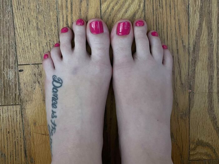 Close-up of feet with pink painted nails and a rare tattoo on one foot, showcasing unique body features.