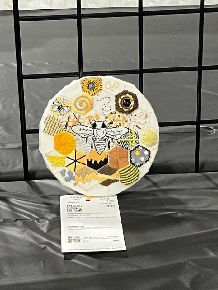 Circular stunning embroidery creation with a bee surrounded by honeycomb patterns and other designs, inspiring hobby.