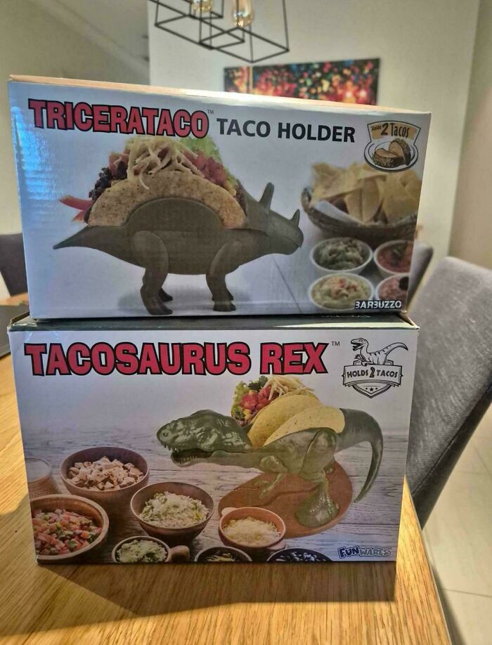 Tricerataco and Tacosaurus Rex nonsensical taco holders shaped like dinosaurs, holding two tacos each.