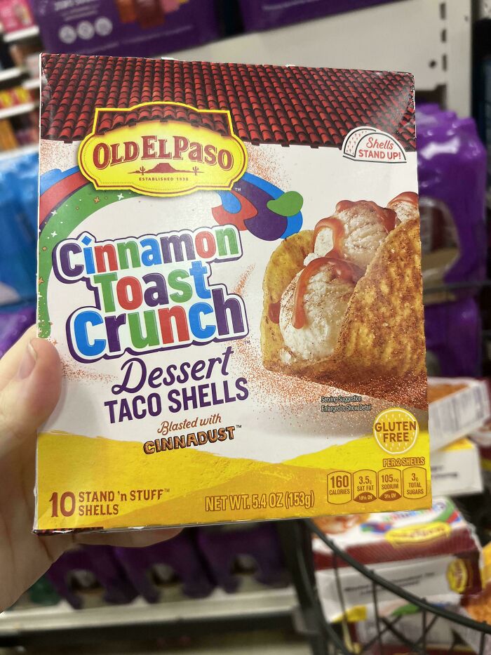 Hand holding a box of Old El Paso cinnamon toast crunch dessert taco shells, a nonsensical edible product.