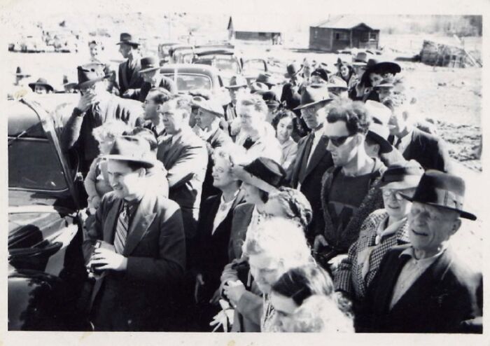 Crowd of people in vintage clothing gathered outdoors around a car, a photo that seems normal until you learn the mysteries behind it