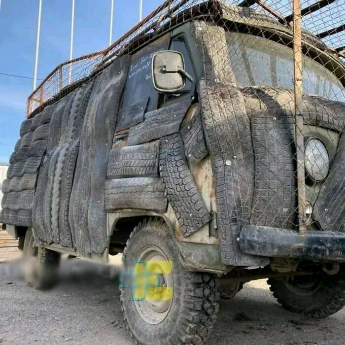 Rusty van covered entirely with old tires including doors and windows, showcasing one of the most nonsensical things that actually exist.