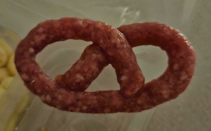 Pretzel-shaped raw sausage meat on a clear surface showcasing one of the most nonsensical things that actually exist.