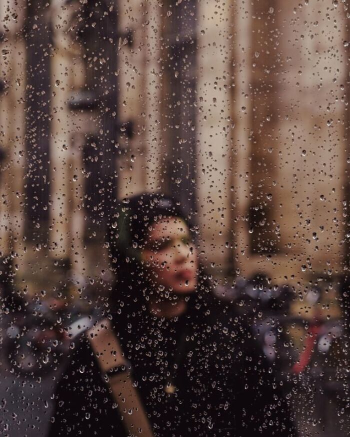 Blurred street photo of a person seen through a rain-covered window, showcasing stunning street photography.