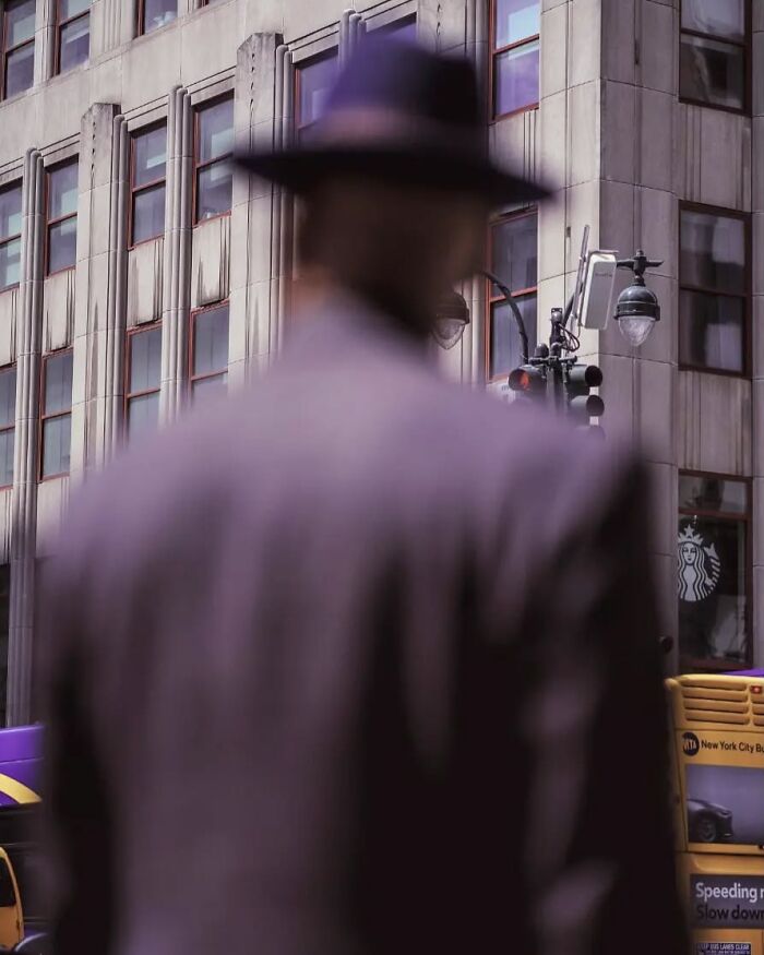 Blurred man wearing hat in urban setting capturing street photos by Greek photographer Marina Nota.