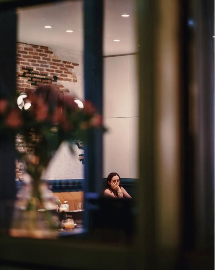 Woman sitting alone in a cozy interior, captured in a stunning street photo by Greek photographer Marina Nota.