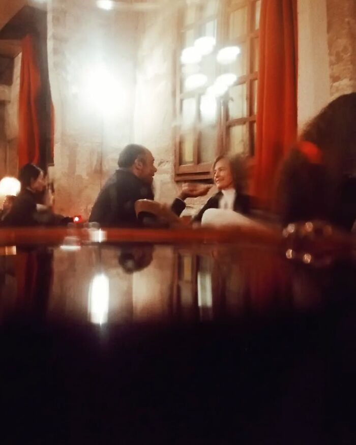 Couple engaged in conversation inside a cozy venue captured in stunning street photos by Greek photographer Marina Nota.