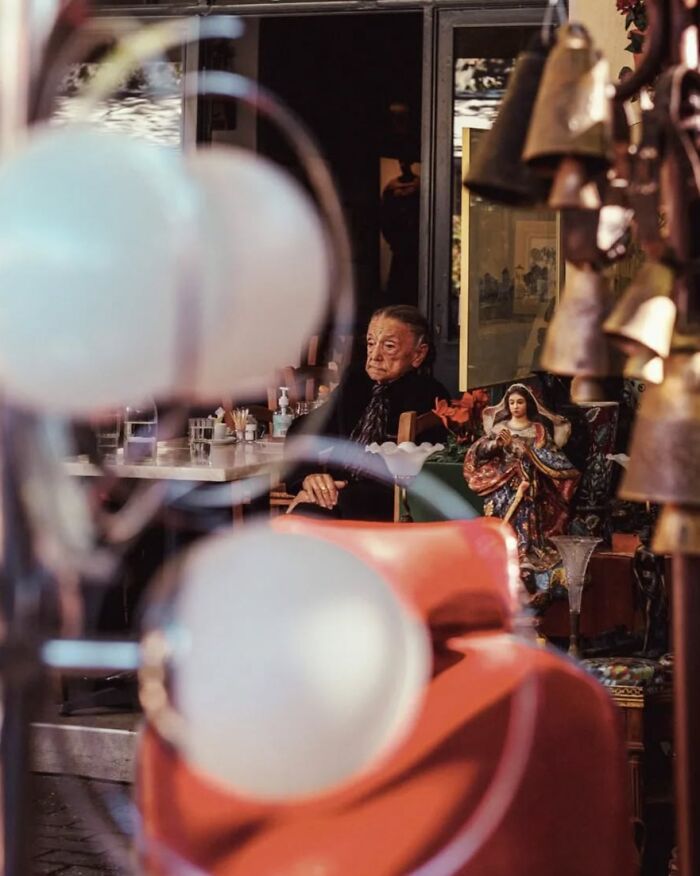Elderly person sitting inside a cafe captured in stunning street photos by Greek photographer Marina Nota.