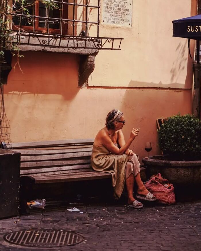 Woman sitting on a bench enjoying a street moment in warm tones captured in stunning street photos by Greek photographer.