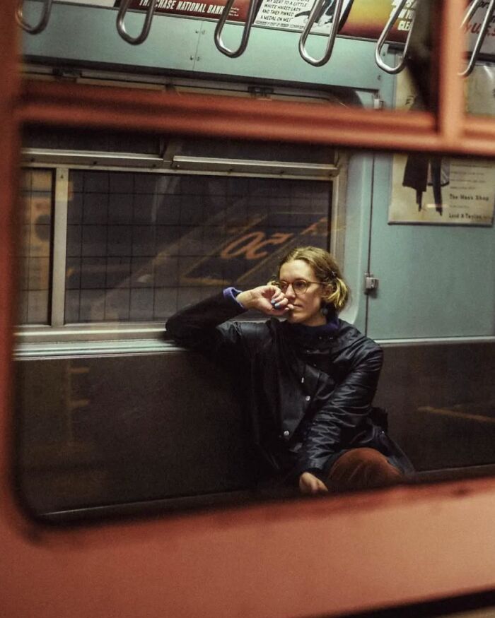 Woman wearing glasses sitting alone on a subway bench, captured in a stunning street photo by Greek photographer Marina Nota
