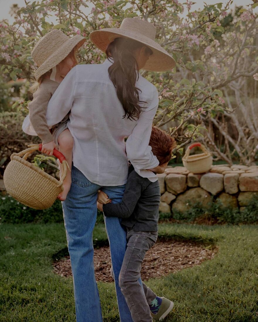 Meghan Markle with Prince Harry's kids outdoors, surrounded by greenery, wearing hats and casual spring outfits.