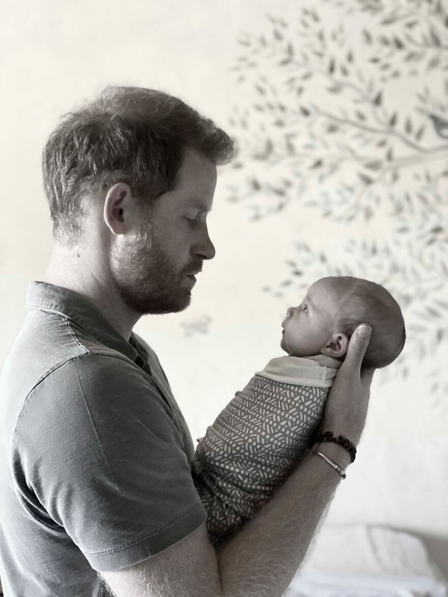 Prince Harry tenderly holding and looking at his newborn baby, highlighting Meghan Markle and Harry's kids&rsquo; lives away from palace.