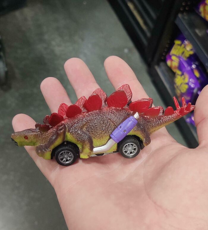 Small toy combining a stegosaurus dinosaur with car wheels, showcasing one of the most nonsensical things that actually exist.