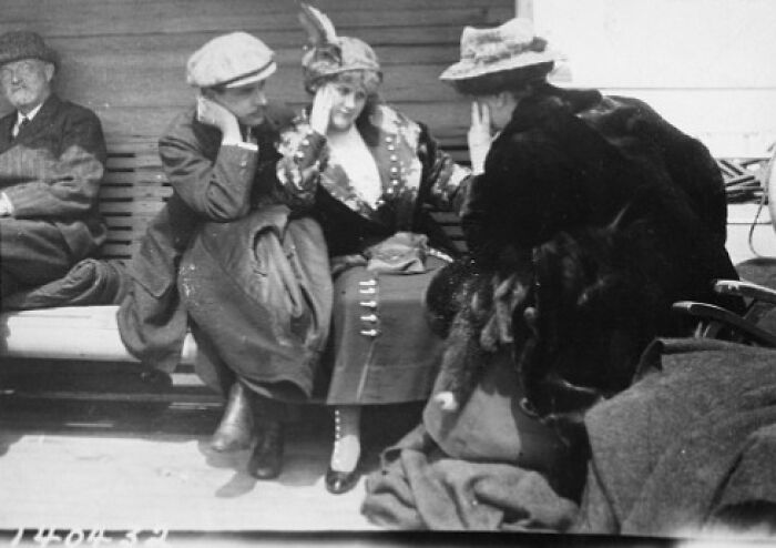 Passengers dressed in early 20th-century attire seated and conversing on the deck in a rare historical Titanic photo.