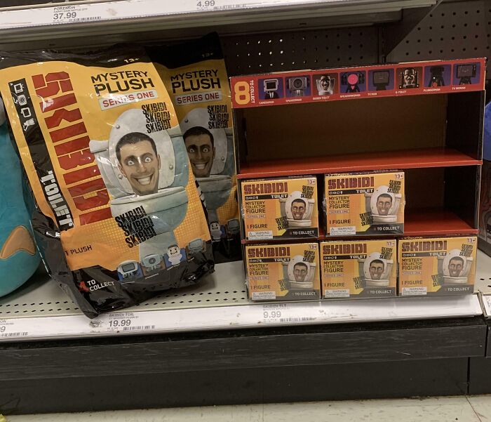 Shelf display of nonsensical mystery plush and figures featuring a cartoonish character with exaggerated facial expressions.