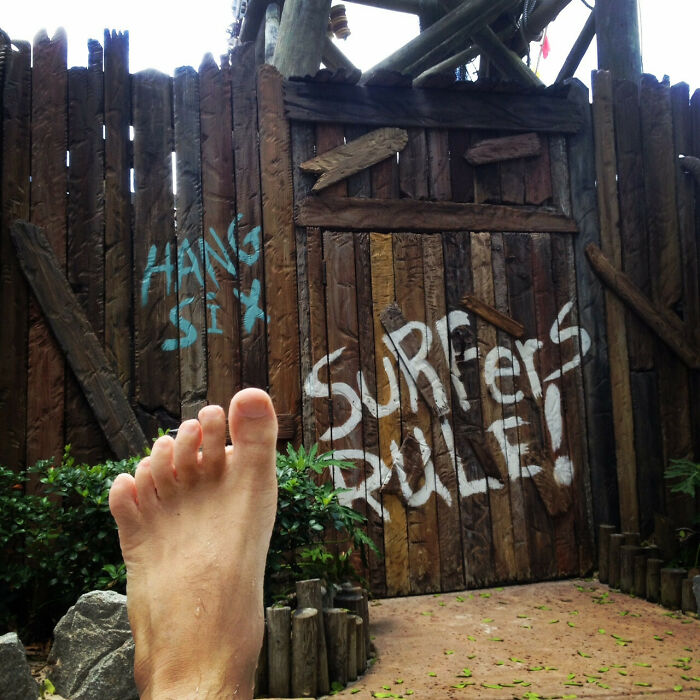 Close-up of a bare foot in front of a wooden fence with graffiti, illustrating rare and surprising things about bodies.