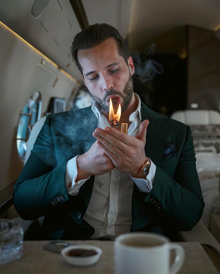 Tristan Tate in a suit lighting a cigar on a private jet, symbolizing Tristan Tate&rsquo;s net worth influenced by legal turmoil in 2025.