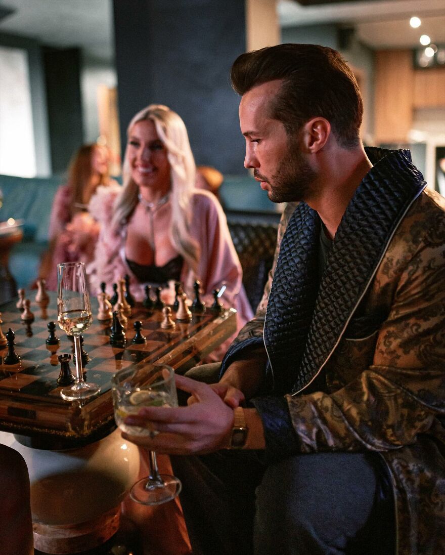 Tristan Tate in a robe playing chess while holding a drink, highlighting Tristan Tate net worth amid legal turmoil in 2025.