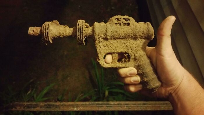 Hand holding a rusty old object covered in dirt, an example of people finding something old with no clue what it is.
