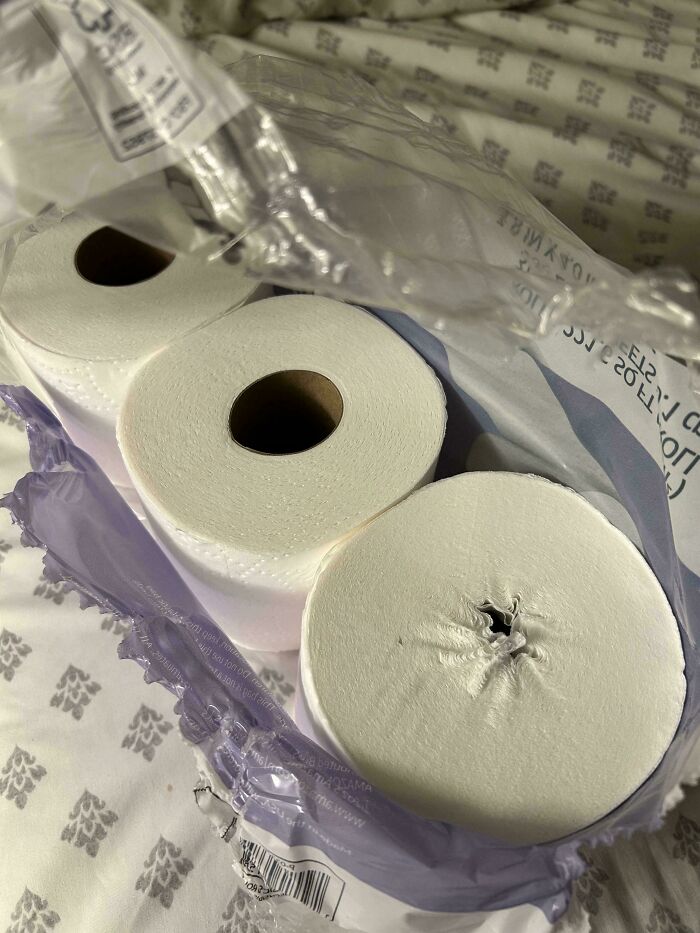 Three rolls of toilet paper with one roll having a weird pinched hole in the center, a weird and cursed picture.