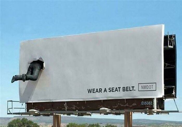 Billboard showing legs of a person stuck through with a seat belt message, a funny and weird billboard example.