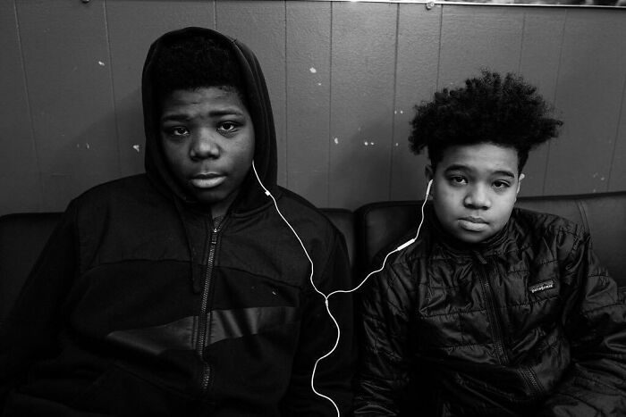 Two children of the world sharing earphones in a powerful black and white photograph by Andrea Torrei.