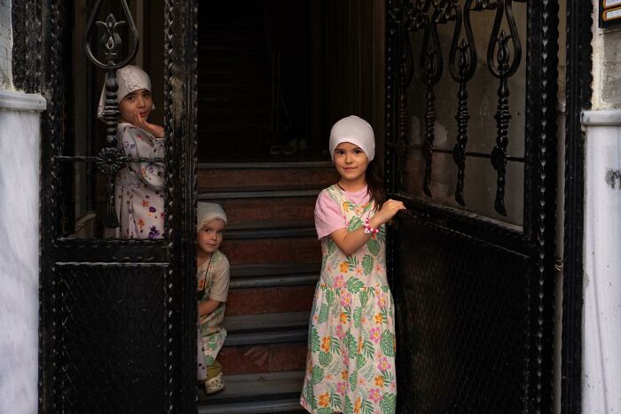Three children standing at a doorway, captured in a powerful photograph showcasing children of the world.