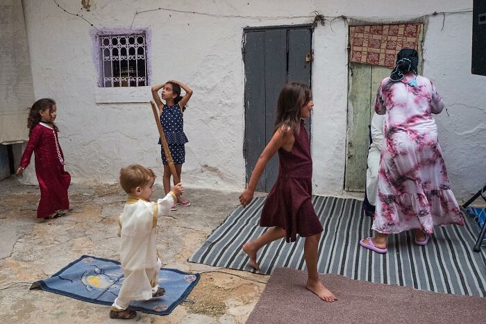 Children of the world playing together outdoors near a home, captured in a powerful photograph by Andrea Torrei.